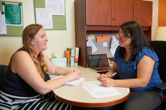 A staff member advises a student in their office.